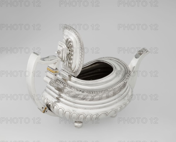 Teapot by George McHattie fl. 1799–ca. 1825, English Regency style. Rectangular teapot with rounded edges, supported by four ball feet. Decorated with hoarding ornament at the base; above are two smooth half-cylinders with an engraved braided band at the narrowing. Upper edge has a collar decorated with hoardings and flowers. Hinged rectangular profiled lid edged with tendril; high axis spout shaped like a spout. Broken ear with bone insulators. Dated 1819–1820, made in Edinburgh, Scotland. Vessel. Height 16 cm; width 28.5 cm; depth 13.5 cm; weight 735 g., A silver teapot with an open hinged lid sits against a neutral background, showing a rounded body with decorative ridges and embossed patterns; the lid has a raised floral-like design and an ornate border, and the interior visible through the opening appears dark. The teapot has a curved spout and a wide handle with small rectangular accents in a yellowish-gold color near its attachments. The body rests on small rounded feet and feat...
