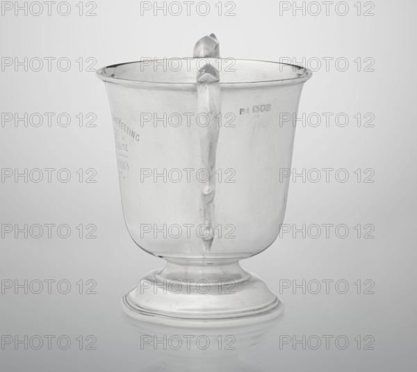 Prize cup, goldsmith/silversmith/corporate maker fl. 1859-. Scrap - purchase, occasional inscriptions; sports award, horse racing cross-country steeplechase. Cup on a circular, arched, profiled base and a short shaft; semi-ovoid body, flattened at the bottom; slightly flared upper edge bordered with a half-cylinder, two volute handles on the sides. Engraved inscription on the belly: BURSTON POINT TO POINT MEETING / 22nd APRIL 1911 / OPEN STEEP LECHASE / WON BY / MR H.DETERDING'S / \NIGGER\, 1910/1911. England, London, Great Britain. Vessel; height 16.5 cm, width 23.5 cm, depth 14.5 cm, weight 500 g., A shiny metallic cup with a rounded base and a flared rim sits on a reflective surface, showing smooth curved sides and a single handle that attaches near the rim and extends down the body; the cup and its base exhibit a few surface scratches and subtle reflections, and the visible colors are shades of silver, gray, and white.