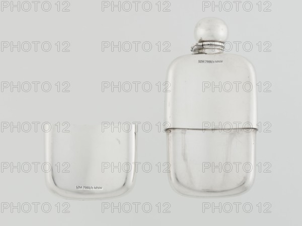 Hip flask, George & Sons Birmingham; goldsmith's firm; fl. 1825–1928 maker; so-called cuboid hip flask with rounded corners; smooth, slightly curved; spout in the form of a narrow neck with an applied spherical hinged stopper; bottle narrowed in the lower part from the middle; on this part a slide-in container — a cup masking the narrowing is placed; the interior of the cup and the spout are gilded; 1907/1908; England, Birmingham; vessel; height 15.5 cm, width 7.6 cm, depth 2.7 cm; weight 240 g, A pair of metallic objects with smooth rounded shapes sit against a light gray background; one is a larger two-part container with a rounded cap and a hinged neck, showing a shiny silver surface with subtle scuffs and reflections, and the other is a smaller rounded metallic cup or cover with a similar silver finish and minor surface marks.