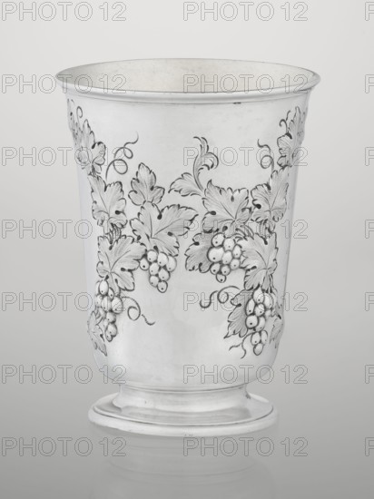 Conical mug by Barnard, Edward & Sons Ltd, London goldsmith's firm, fl. ca. 1680– ; silver conical mug on a circular foot; belly decorated with relief vine wreaths, one with an English inscription: Carola Kremser / from / SMS/ Nov: 1893. Slightly flared, profiled rim. Gilded interior. Dated 1861/1862. England, London. Vessel; height 12 cm, diameter 9 cm, weight 175 g. Materials/technique: silver, relief decoration; provenance notes: purchase, dedications., A tall metal cup with a flared rim and a rounded foot, decorated with embossed grape clusters and large stylized leaves and curling tendrils, shown against a plain light background; the cup and decorations appear in shades of silver and gray with subtle darker gray shading on the embossed details.