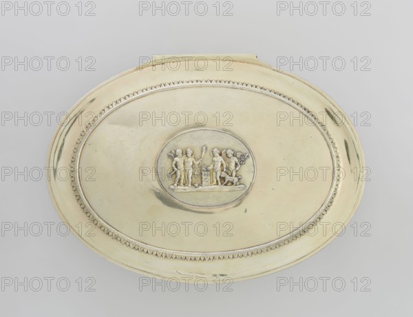 Oval toilet box by Thomas I Pitts fl. 1755–ca. 1793, goldsmith. Georgian, George III style, England, London, 1780–1781. Oval box on four volute feet formed of acanthus leaves; lower edge decorated with a band of bay leaves, above them laurel festoons with suspended medallions containing rosettes, upper edge with an anthemion frieze. Hinged recessed cover bordered with a band of bay leaves; central medallion on the cover with a relief of four putti at a sacrificial altar. Decorated in relief with festoons, palmettes, anthemions, bay leaves. Materials: toilet accessories. Dimensions: height 12 cm; width 27.1 cm; depth 20 cm; weight 1627 g., A large oval metallic object with a pale yellow and silver sheen rests against a light gray background, featuring a raised central oval area with a bas-relief scene of a group of small human figures and a small animal, surrounded by a decorative border with a repeating triangular pattern and smooth inner and outer bands in shades of pale yellow and si...