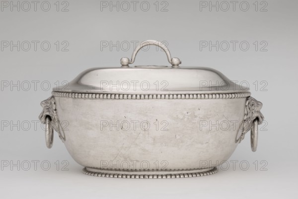 Vase with cover and platter, by Marcin Holke fl. ca. 1765–ca. 1792, goldsmith; tableware elements, vases; 18th century, Poland, Warsaw; vessel; height 20 cm, width 46 cm, depth 31.5 cm, A silver-colored covered dish with a rounded body and domed lid, featuring a central arched handle on top and a beaded decorative rim along the lid and base; the body shows a slightly worn surface with subtle scratches and marks, and each side has a sculpted lion-head ornament holding a ring, all set against a neutral gray background with tones of white and light gray.