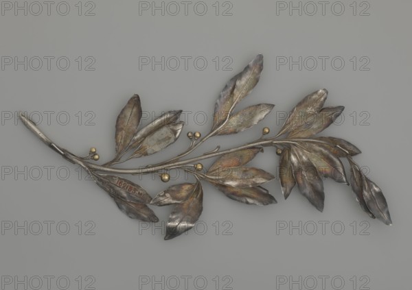Laurel branch; creator, Paderewski, Ignacy Jan 1860–1941; end of 19th century; unknown locality; varia; height 29.7 cm; width 14.5 cm; weight 105 g, A metallic branch-like object with a group of elongated leaves and small spherical buds rests against a plain neutral background; the leaves show a range of colors including silver, gray, brown, greenish and subtle iridescent tones, and the small round buds are a golden color, while the background is a uniform light gray.