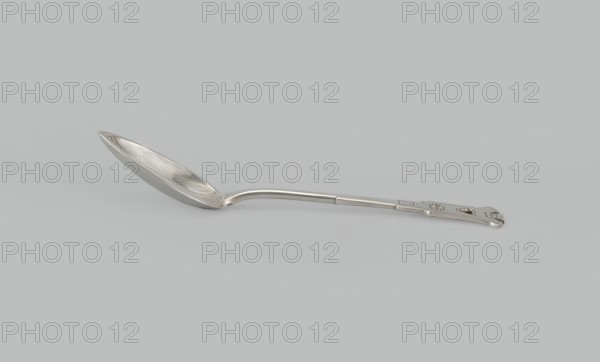 Dessert spoon, Jarra, Marcin 1852–1938 goldsmith; maker, Paderewski, Ignacy Jan 1860–1941 - testamentary bequest provenance, Zakopane style, Dessert spoon with an ovoid, smooth, pointed scoop, a stepped handle ending in a stylized crown and decorated with an engraved geometric ornament stylized to resemble Zakopane style, early 20th century, Poland, Kraków, cutlery, height 16 cm, width 3 cm, weight 35 g, A single metal spoon lies horizontally against a light gray background, showing a reflective silver surface with subtle highlights and shadows; the bowl of the spoon is elongated and slightly curved with visible wear and faint marks, the handle is straight with a gentle bend near the bowl and ends in a flat decorative section that has a few small cutout shapes and raised details, and the overall colors visible are silver and shades of gray.