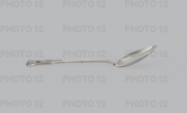 Dessert spoon, Jarra, Marcin 1852–1938 goldsmith, Paderewski, Ignacy Jan 1860–1941 - testamentary bequest provenance, Zakopane style, Dessert spoon with an ovoid, smooth, pointed scoop, a stepped handle ending in a stylized crown and decorated with an engraved geometric ornament stylized to resemble Zakopane style, early 20th century, Poland, Kraków, cutlery, height 16 cm, width 3 cm, weight 35 g, A single metal spoon lies horizontally on a pale gray background, showing a long narrow handle with a decorative flattened end and a slightly curved shaft leading to an elongated oval bowl; the spoon and background display shades of silver, gray, and subtle reflections of white.