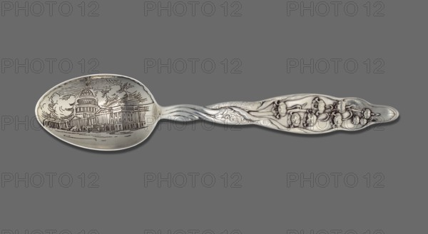 Souvenir spoon, Whiting Manufacturing Co fl. 1866–1926. Souvenir spoon with egg-shaped scoop bearing a representation of the Capitol building in Washington; flat handle with a relief lily-of-the-valley sprig; engraved IP monogram tied on the reverse. Lily of the Valley pattern introduced in 1885; late 19th century. Cutlery, sterling silver; height 15 cm, width 3.1 cm, weight 25 g. Made in Bridgeport, United States of America., A silver spoon with an ornate handle featuring raised floral and scrollwork details, a twisted neck connecting to an oval bowl that has an engraved architectural scene and swirling cloud-like lines; the object rests against a flat gray background and the visible colors are silver and gray.
