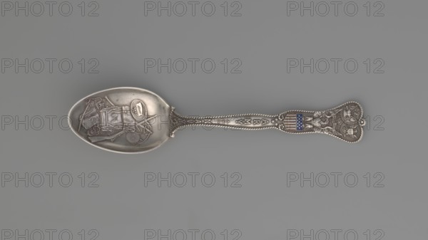 Souvenir spoon, Gorham Mfg. Co. goldsmith's manufactory; fl. 1865-. Souvenir spoon with an ovoid scoop decorated inside with a relief representation of armament and uniform accessories of the American infantry and cavalry; flat, profiled, widening handle with a heart-shaped tip, edged with twisted wire imitating aglets. Along the handle is the inscription ARMY AND NAVY; above it an enameled United States flag in a cartouche, held in the talons by an eagle with upraised wings, on the wings a sash with the inscription E PLURIBUS UNUM. At the end of the handle, two emblems — the Navy US Navy and the Army US Army — in circular reserves; on the reverse of the handle, accessories of the United States Navy — an anchor with crossed swords, below crossed cannon barrels. Late 19th century, Providence, United States of America. Souvenir, cutlery; height 15 cm, width 3.3 cm, weight 35 g., A silver-colored ornate spoon lies horizontally against a gray background, with an oval bowl on the left and a...