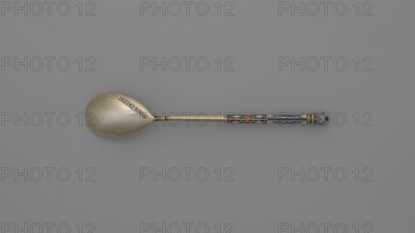 Souvenir spoon by Nikolai Struliev fl. 1886–ca. 1910, goldsmith. Decorative spoon with teardrop-shaped scoop and angular handle, half decorated with a geometric ornament of colored cellular enamel, topped with a bowl. Dated 1886–1894. Moscow, Russia. Cutlery; height 12.5 cm; weight 20 g., A single spoon lies horizontally against a gray background, with a metal bowl on the left and a decorative handle on the right; the bowl is a dull gold tone with a slightly worn surface and an oval shape, and the handle is a warmer gold metal interrupted by a patterned section featuring a group of enamel inlays in blue, white, red, and turquoise set within dark outlines, ending in a flared terminal with similar blue enamel accents.