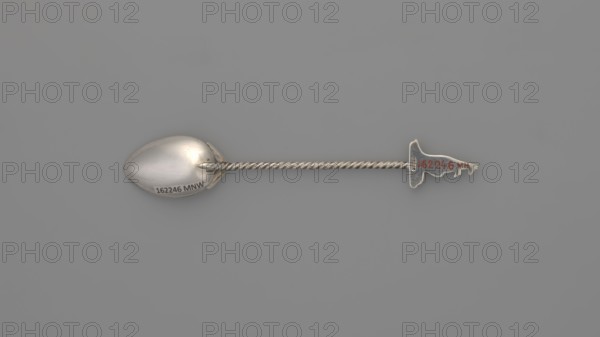 Souvenir spoon, Paderewski, Ignacy Jan 1860-1941; souvenir from Paderewski's tour of Australia and New Zealand in 1904; early 20th century before 1904. Egg-shaped scoop with a pointed tip; twisted wire handle topped with a semi-plastic kangaroo; decoration includes kangaroos and Australian fauna. Cutlery, varia. Dimensions: length 12.5 cm, width 2.2 cm, weight 15 g. Role or, A single metal spoon lies horizontally against a smooth gray background, showing a rounded bowl on the left, a long twisted handle in the center, and a decorative finial shaped like an irregular silhouette on the right; the spoon and handle have a reflective silver color with subtle highlights and shadows, and the finial shows a small area of reddish coloration.