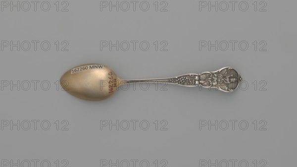 Souvenir spoon, Mechanics Sterling Co Attleboro; goldsmith's firm; fl. 1896–1955. Souvenir spoon with ovoid scoop, gilded, decorated with an engraved representation of a Victorian-style building resembling a French chateau, built on a rock in 1896 with the inscription in italics SAN FRANCISCO CLIFF/HOUSE; a widening handle with a profiled edge decorated with a relief ornament on both sides; on one side an inscription along the handle CALIFORNIA 1849 adoption of the California Constitution and the beginning of the gold rush, above it a gold prospector; in the finial a bear symbolizing the state of California; on the reverse fruit characteristic of California; in the finial the state emblem — a seated Minerva, next to her a lying bear, in the background a landscape. Date: 1896–1907. Place of origin: United States of America; Attleboro. Classification: cutlery. Dimensions: length 10 cm, width 2 cm, weight 5 g., A single ornate spoon lies horizontally against a plain gray background, showi...