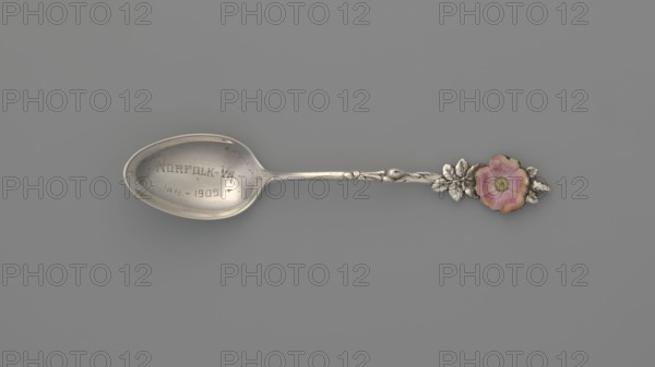 Souvenir spoon, Reed & Barton Taunton; goldsmith's firm; fl. 1840–, maker, Hennegen Bates & Co fl. 1869–1955 maker, Paderewski, Ignacy Jan 1860–1941, roses, flowers, Paderewska, Helena 1856–1934 - monogram, Wilde Rose cutlery model, Ovoid dipper with engraved inscription NORFOLK - VA - / - JAN. - 1905; on the reverse the monogram HP Helena Paderewska in italics. Handle in the form of a floral sprig terminating in an enameled wild rose flower. Design identified as Wild Rose, ca. 1905, Taunton manufacturer, Baltimore jewelry company, United States of America, cutlery; length 13 cm, width 2.1 cm, weight 20 g, A single ornate spoon is shown lying horizontally on a plain gray background, with a rounded bowl on the left and a decorative handle on the right; the spoon's metal surface is silvery with areas of slight tarnish, and the handle features a floral motif with sculpted leaves in silver and a painted flower in shades of pink and yellow.