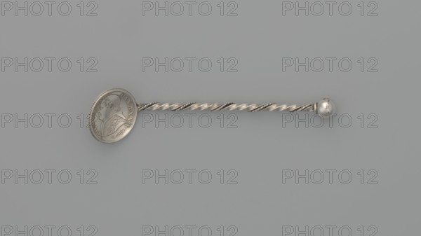 Souvenir spoon, souvenir spoon with a scoop made of a 10-soldo coin with an image of Pope Pius IX in profile on the obverse and the inscription PIVS IX PON MAX A XXII; on the reverse the inscription STATO PONTIFICO 50 R CMI and in the middle in a laurel and oak wreath - 10 / SOLDI / 1868. The handle is made of twisted wire with a ball at the end. 1868 coin, end of the 19th century, Italy. Cutlery, varia. Length 7.5 cm, width 1.8 cm, weight 5 g., A slender metallic object lies horizontally on a muted gray background, showing a twisted rod with alternating smooth and ridged spirals that have a silvery sheen; one end features a round flat disk with a raised profile of a person in relief and decorative patterns around its edge, while the opposite end terminates in a small polished spherical knob with slight surface blemishes.