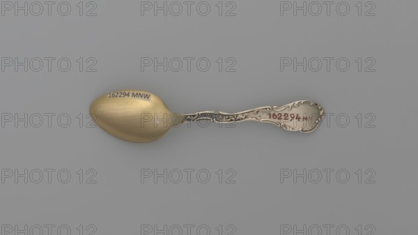 Souvenir spoon, Shepard Mfg. Co. fl. 1893–1923. Silver souvenir spoon. Ovoid scoop with engraved view of buildings and the inscription JACKSONS / BIRTHPLACE / NASHVILLE / TENN. Flat handle with irregular edges made of channel sections; the inscription TENNESSEE along the handle, above which is a man with a pickaxe. Handle widened at the end with relief depictions of a plow, a sheaf of wheat above it the Roman numeral XVI, cotton, with the inscription AGRICULTURE underneath, and a ship below with the inscription COMMERCE below. These are the emblems of the state of Tennessee. XVI indicates the state's serial number. State motto: Agriculture Commerce. 19th/20th century. Cutlery. Length 9.5 cm, width 2.2 cm, weight 10 g. Makers’ role: goldsmith company. Subject: Paderewski, Ignacy Jan 1860–1941., A single ornate spoon lies horizontally on a plain gray background, with the bowl on the left and the handle on the right; the bowl has a warm golden color with subtle brushing marks and a few sm...