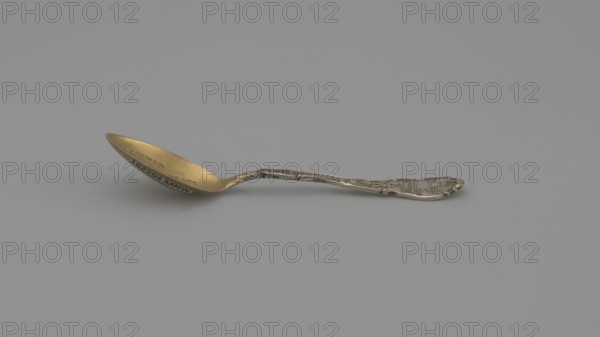 Souvenir spoon by Shepard Mfg. Co. fl. 1893–1923. Silver souvenir spoon, ovoid scoop with engraved view of buildings and the inscription JACKSON'S / BIRTHPLACE / NASHVILLE / TENN. Flat handle with irregular edges made of channel sections; the inscription TENNESSEE along the handle, above which is a man with a pickaxe. Handle widened at the end with relief depictions of a plow, a sheaf of wheat above it the Roman numeral XVI, cotton, with the inscription AGRICULTURE underneath, and a ship below with the inscription COMMERCE. These are the emblems of the state of Tennessee. XVI denotes the state's serial number. State motto: Agriculture Commerce. 19th/20th century. Made in Melrose Highlands, United States. Cutlery; length 9.5 cm, width 2.2 cm, weight 10 g., A single ornate spoon lies on a flat surface against a plain background, showing a metallic appearance with gold visible on the bowl and silver on the handle; the spoon has decorative raised patterns along the handle and a slightly cu...