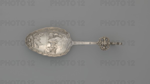 Decorative spoon, Paderewski, Ignacy Jan 1860-1941 - testament provenance, pastoral scenes. Decorative spoon with an oval scoop with a relief pastoral scene framed in a pearled border: a woman sits under a tree with two sheep beside her; floral decoration at the bottom; irregular, wavy scoop edge. Flat handle with a volute ending, decorated with an openwork section depicting a winged putto head and a plastic lion standing on its hind legs. Late 19th century, Netherlands. Cutlery, varia. Height 14 cm, width 4.3 cm, weight 20 g., A single ornate spoon lies horizontally on a plain background, showing a scalloped bowl with embossed decorative motifs including floral shapes and figural relief; the spoon has a long flat handle leading to a decorative openwork terminal with a looped extension. The visible colors are silver with darker tarnished areas and a neutral gray background.