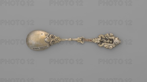 Decorative spoon, Neresheimer Hanau; goldsmith's workshop; 1890-, goldsmith's company author, Paderewski, Ignacy Jan 1860-1941 - testament provenance, grotesques, neo-Renaissance style, putti, Decorative spoon with a circular scoop and a profiled handle topped with a grotesque with a putti standing in an arcade decorated with roses, late 19th century, Germany, Hanau, cutlery, varia, length 11 cm, width 2.4 cm, weight 20 g, An ornate metal spoon lies horizontally on a plain gray background, showing a rounded bowl with a slightly worn, tarnished surface and a decorative handle featuring intricate scrollwork and a sculpted figure; visible colors include shades of silver, gray, muted gold, and small areas of darker tarnish.