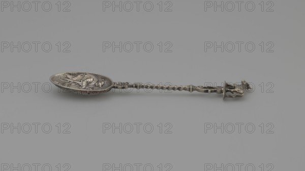 Souvenir spoon, Paderewski, Ignacy Jan 1860-1941, rural scenes, genre scenes, cows, peasants. Decorative spoon with an ovoid scoop containing a genre scene inside a barn depicting resting peasants in peasant costumes with hats. In the foreground a man sits on a stool with his back turned; to his left a standing man, his right hand leaning on a rake and his left holding a pipe raised to his mouth; in the background a seated man with his hand resting on his knee. Twisted wire handle finished with a cow figure wearing a bell. Unmarked, late 19th century, Netherlands, cutlery, varia; length 11 cm, width 2.6 cm, weight 15 g., A single ornate metal spoon lies horizontally against a plain light gray background, showing a shallow oval bowl with raised decorative relief inside and a twisted, sculpted handle that ends in a small three-dimensional figure; the visible colors are shades of silver and gray with subtle darker patina tones.