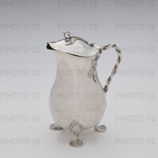Jug, Holke, Marcin fl. ca. 1765–ca. 1792 goldsmith, tableware, flowers motif, before 1792, Poland, Warsaw; vessel, height 13.2 cm, width 10 cm, depth 6 cm, weight 215.8 g, A silver pitcher with a rounded body and a hinged lid sits on a pale background; the pitcher has a curved spout, a twisted decorative handle, and ornate feet with a shell-like motif, and there are floral and leaf embellishments on the lid and near the handle, with visible colors including silver, gray, and subtle darker tarnished areas.