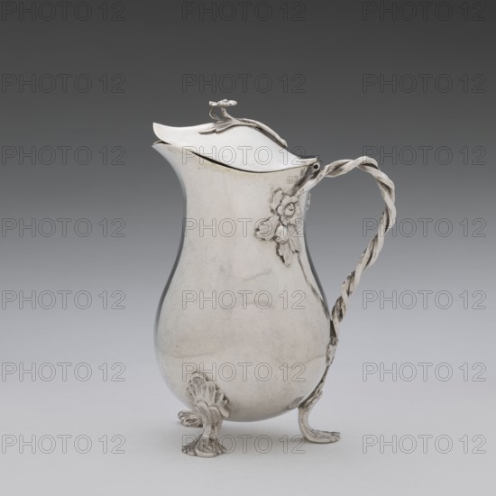 Jug, Holke, Marcin fl. ca. 1765–ca. 1792 goldsmith, tableware item decorated with flowers, before 1792, Poland, Warsaw; vessel; height 13.2 cm, width 10 cm, depth 6 cm, weight 215.8 g, A reflective metal pitcher with a gently curving, bulbous body and a hinged lid sits on a smooth surface; the pitcher is supported by ornate claw-like feet and has a twisted, rope-style handle attached to its side, where a decorative floral relief is visible; the lid features a small sculpted finial and a curving edge, and the overall colors in the image are shades of silver on the pitcher, a gradient gray background, and a pale gray surface beneath.