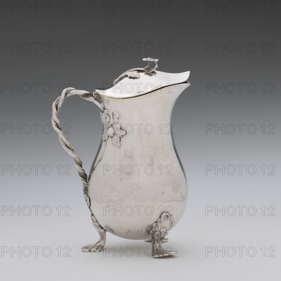 Jug, Holke, Marcin fl. ca. 1765–ca. 1792 goldsmith, tableware jug decorated with flowers, before 1792, Poland; Warsaw; vessel; height 13.2 cm, width 10 cm, depth 6 cm, weight 215.8 g, A metallic pitcher with a smooth reflective surface in silver tones stands on a pale surface against a gradient dark-to-light gray background; it has a curved body tapering toward a narrow neck and a hinged lid with a small decorative finial, a twisted rope-like handle attached to the side with floral appliqué, and three ornate feet with shell-like motifs, showing a few subtle scuffs and tarnish marks in darker gray.