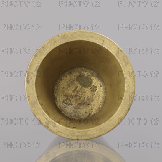 Gwicht, unknown creator; Szewczykowski, Roman 1849–1901 — ; measures and weights; object in the shape of a truncated cone with markings: 4 M engraved inside and on the side 76; weight 935.18 g; end of 18th century; Germany; height 6.2 cm, width 8.6 cm, A top-down view of a cylindrical metallic cup with a golden-brass color, showing the interior with visible wear, scratches, and darker tarnished spots; the rim has concentric ridges and the inner walls are smooth with slight discoloration; the bottom interior shows mottled areas and textured marks; the object is reflected faintly on a glossy surface beneath, and the background is a muted light gray.