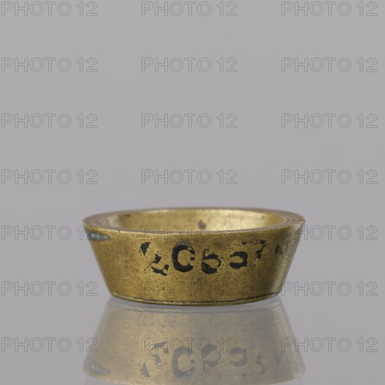 Gwicht; creator, Szewczykowski, Roman 1849–1901 associated name. In the shape of a truncated cone, marked inside 1. Weight 12.8 g. 18th century, Europe; Germany, Berlin. Height 0.9 cm; width 2.6 cm., A small metallic ring-shaped object with a flared outer edge sits on a reflective surface, showing a mirrored reflection beneath it; the object is primarily gold in color with areas of darker wear and a few spots of blue-green discoloration, and the background is a uniform light gray.