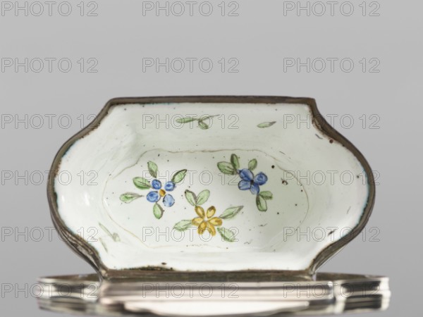 Double snuffbox, LZ enameller; France?; fl. ca. 1700. Double-sided snuffbox, tall, narrowed halfway up; slightly bulging lids, framed by silver, profiled fittings, white-enameled, decorated with colourful scenes from the story of Samson depicted against a landscape painted in grisailles. On the sides: two representations — Samson going to the Philistine city of Timna, shown the way by three women, and Samson fighting a lion. On the lids: Samson carrying the door the city gate to the top of the mountain opposite Hebron and Samson taking honey from the lion's mouth. On the reverse of the lids: two landscapes with architecture painted in grisailles and colourful flowers painted in the bottoms. Early 18th century, France, enamelling, smoking accessory. Height 7 cm; width 7.7 cm; depth 4.7 cm., A shallow, scalloped dish with a white interior and a metallic rim shows hand-painted floral motifs including a few blue flowers, a yellow flower, and several green leaves; the rim appears dark brown...