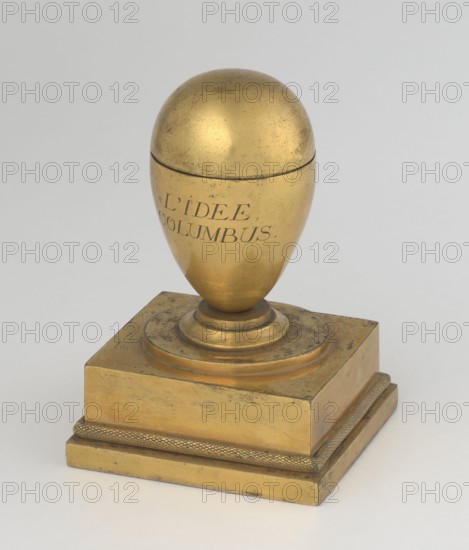 Inkwell, creator, attributed to Tadeusz Bylewski 1866–1939; early 19th century, France, inkwell; height 13.5 cm, width 9.4 cm, depth 8.4 cm, A metallic object with a rounded egg-shaped top set on a stepped square base, all in a worn golden tone with darker scuff marks and patina; the egg portion has a visible seam near its upper third and sits on a circular plinth that transitions to the square pedestal, which shows textured edging along its lower tier; the background is a smooth light gray.