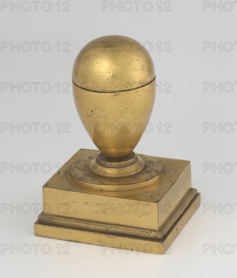 Inkwell, creator possibly Bylewski, Tadeusz 1866–1939, early 19th century, France, inkwell; height 13.5 cm, width 9.4 cm, depth 8.4 cm, A polished metallic object with a rounded egg-shaped top sitting on a stepped square base, all in a gold color with areas of darker patina and small surface scratches; the rounded top has a visible seam and a smooth reflective finish, while the base shows a textured band around its lower edge and flat horizontal surfaces with subtle wear.