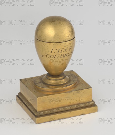 Inkwell, unknown creator; early 19th century, France, inkwell; maker possibly Tadeusz Bylewski 1866–1939; height 13.5 cm, width 9.4 cm, depth 8.4 cm, A metallic object with a gold tone sits on a pale background; it has an egg-shaped top with a visible seam near its middle and a rounded base mounted on a stepped circular plinth, which in turn rests on a square block base with a textured band around its lower edge; the surface shows some darker spots and wear, with colors including gold, darker tarnished brown areas, and a light gray background.