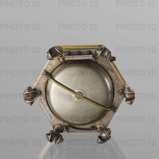 Tiled clock, Gugenmus, Michael 1705-1775 watchmaker, rococo style, regency ornament, tiled clock, table clock, hexagonal, gilded bronze on six volute legs, glazed side walls; silver-plated ring-shaped dial with black Roman numerals for hours and Arabic minutes, with two winding holes; center engraved Regency-Rococo cartouche with signature Gugenmos/Varssavie; hinged flap closing the mechanism; on the front plate of the mechanism a modest bun, a hammer with an engraved bronze head. Signature: Johann / Michael / Gugenmus / A Varsovie. Mechanism with a strike repeater, with a handle on the side wall under the upper edge. 2nd half of the 18th century, Poland, Warsaw. Timepiece; height 8.5 cm, width 13.5 cm, depth 13.5 cm., A metallic hexagonal object with a circular domed center held by a diagonal bar, showing a mix of brass, silver, bronze, and darker tarnished metal tones; each corner of the hexagon has a rounded ornamental knob with layered ridges, and several small screws and hinge-lik...