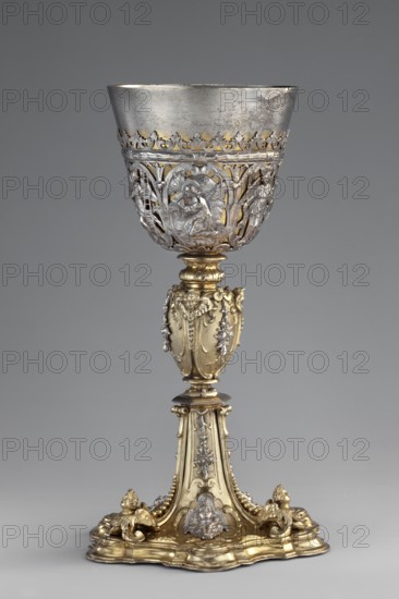 Mass chalice, Schwestermüller, David I fl. 1628–1678 goldsmith; Prayer in the Garden of Olives, Jesus Christ, Passion depictions, Arma Christi, Mystical Winepress, Ecce homo iconography. Mass chalice on a profiled multi-leafed plinth and a quadrangular foot decorated with relief winged angel heads in conch-volute reserves; campanulas and plastic angel heads on division edges; ovoid nodus with similar decoration. Goblet with an openwork basket carved with Passion scenes — the Prayer in the Garden of Olives, Ecce Homo, Christ in the Mystical Winepress — among which are angels bearing the Arma Christi. Considered a vasa sacra, symbolically associated with the tomb and earthly sufferings of Christ; Christ depicted as the man of sorrows with the instruments of his Passion. Graphic patterns likely compiled from several engravings; auricular ornamentation with Netherlandish sources and depictions showing features of late 16th-century Italian engravings cf. Agostino Carracci's Ecce Homo, 1587,...