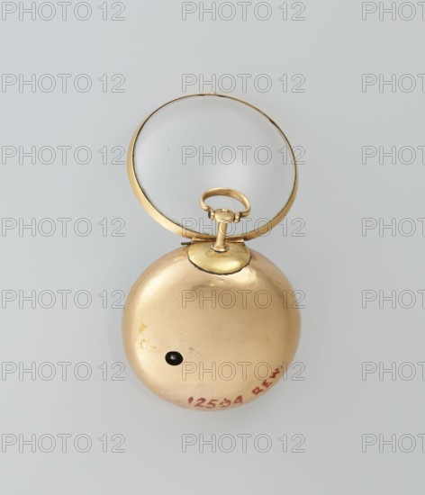 Pocket watch in case, maker: M. Cradelle fl. ca. 1750, watchmaker; mythological scenes; rococo style; double case and outer case covered with lizard, with riveted rosette; mid-18th century; London, England, Great Britain; timepiece; height 6 cm, width 4.5 cm, diameter 3.5 cm dial., A round metallic object with a hinged clear circular lens is shown against a pale grey background; the metal appears gold in color with a smooth, slightly reflective surface and a few small darker blemishes, and the lens has a thin gold rim and shows a faint reflection.