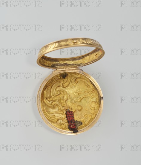 Pocket watch in case; maker: M. Cradelle fl. ca. 1750; watchmaker. Mid-18th century. London, England. Rococo style, mythological scenes. Watch in double case and outer case covered with lizard, with riveted rosette. Timepiece. Height 6 cm; width 4.5 cm; dial diameter 3.5 cm., A small round hinged container shown open, with an ornate interior and lid in metallic gold tones; the interior surface has raised swirling decorative patterns and areas of darker tarnish, and there is a small vertical strip of red and black attached near the inner edge; the exterior rim and lid edge show a gold finish with engraved decorative motifs; the background is a plain light gray.