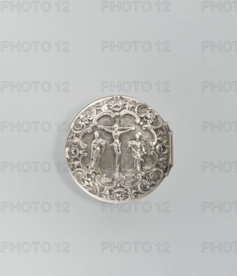 Pocket watch by Joseph Zeidlmayr fl. first half of the 18th century. Watch in a double case; outer case with a frame surrounding the dial and a repoussé depiction of the Crucifixion with Mary and St. John on the back, surrounded by a border of eight C-shaped sections and ornamental decoration. Smooth silver inner case. Silver dial with Roman numerals for hours separated by gold dots and Arabic minute numerals. The reserve bears the signature of the watchmaker Zeidlmayr. Inside, the movement cover has a cutout revealing a bun. The movement is marked: Breslau / Joseph Zeidlmayr. Inside the case are a negative MS mark, a negative mark and a possible goldsmith's mark rosette?, plus two numbers—markings probably made by repairing watchmakers. 1st half of the 18th century; Wroclaw, Silesia. Timepiece., A circular metallic object with ornate raised relief showing a central figure on a cross flanked by two standing figures, all surrounded by intricate scrollwork and floral motifs; the object a...