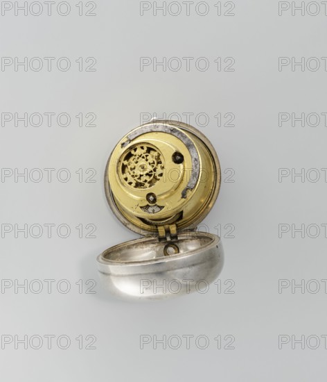 Pocket watch by Joseph Zeidlmayr fl. first half of the 18th century. Watch in a double case: outer case with a frame surrounding the dial and a repoussé depiction of the Crucifixion with Mary and St. John on the back, surrounded by a border of eight C-shaped sections and further ornamental decoration. Smooth silver inner case. Silver dial with Roman hour numerals separated by gold dots and Arabic minute numerals. The reserve bears the signature of the watchmaker Zeidlmayr. Inside, the movement cover has a cutout revealing a bun. The movement is marked “Breslau / Joseph Zeidlmayr.” Inside the case are a negative MS mark, a negative mark and a possibly illegible goldsmith’s mark rosette?, plus two numbers—markings probably made by repairing watchmakers. Date: first half of the 18th century. Place of origin: Wroclaw Breslau, Silesia. Timepiece., An open circular metal object with a hinged lid showing a round inner mechanism; the inner mechanism has a decorative perforated disc and other c...