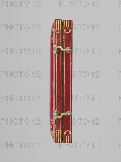Rectangular key case with a hinged lid and two clasp hooks. Trimmed with red leather, with gilded embossing; on the lid, a frame along the edge with an ornament in the corners. In the centre, a ducal mitre. On the underside, a gilded frame along the edge, in the centre a non-gilded embossed rhombus with an inscribed quatrefoil, and in the centre a rhombus with a four-petal rosette. Glued on a printed card with inventory numbers numbers added in ink. Inside: typewritten note describing presentation in 1833 as a wedding gift. 1833, Darmstadt, Germany. Varia. Height 9.8 cm, width 5.9 cm, depth 1.8 cm., A slim closed book seen from its fore edge with a vertical orientation, covered in red leather with worn areas and decorative gold tooling along the edges; two small metal clasps in a dull brass color are attached along the fore edge, each with a rounded fastening and a short hinge, and there are thin gold lines running parallel to the spine; the background is a smooth pale gray.