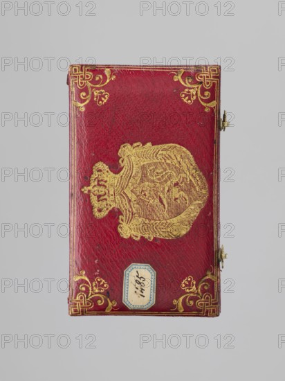 Chamberlain's key case, Rectangular key case with a hinged cover and two clasp hooks. Trimmed with red leather, with gilded embossing; on the cover a frame along the edge with an ornament in the corners. In the centre a ducal mitre. On the underside a gilded frame along the edge, in the centre an ungilded embossed rhombus with an inscribed quatrefoil, and in the centre a rhombus with a four-petal rosette. Glued on a printed card with inventory numbers numbers added in ink. 1833, Germany. Varia. Height 9.8 cm, width 5.9 cm, depth 1.8 cm., A rectangular object with a textured red surface lies against a pale gray background, decorated with ornate gold embellishments including corner flourishes and a central gold emblem that resembles a crowned shield with intricate linework; a small metal clasp is visible on one side and a small decorative label with a blue border is attached near one edge.