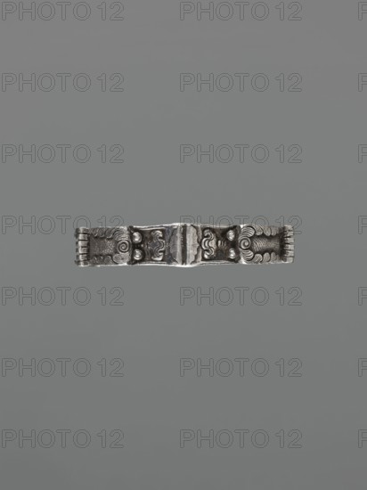 Bracelet, scrap technique; Chinese/Mongolian 19th century ; dragon with pearl motif dragon imagery, hundred antiquities baigu ornament; body/hand fashion accessory; jewelry; height 8.0 cm, width 9.0 cm, weight 281 g., A narrow metallic bracelet centered against a plain gray background, the bracelet showing an aged silver color with darker patina in recessed areas; its surface has embossed and carved decorative motifs including symmetrical curved shapes, rounded raised studs, and textured bands at each end, with a central raised element that appears slightly wider and more ornate than the adjacent sections.