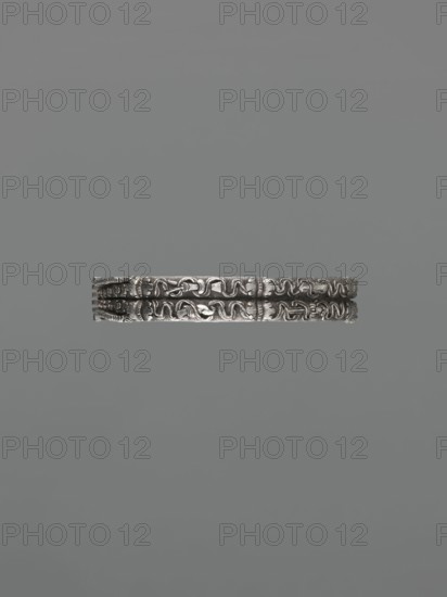 Bracelet; maker, scrap metal; Chinese/Mongolian decorative style; dragons including dragon with pearl motif, body/hand ornament, fashion accessory; hundred antiquities baigu ornament; Chinese culture; possibly 19th century; possible origin: China or Mongolia; jewelry; height 8.0 cm, width 9.0 cm, weight 281 g., A single ornate metallic band with raised decorative patterns is centered horizontally against a uniform gray background; the band appears silver in color with darker shadows in recessed areas, and the background is various shades of gray.