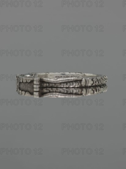 Bracelet, scrap - purchase, purchase provenance; Chinese and Mongolian art; body/hand ornament, fashion accessory; motif: dragon with pearl, hundred antiquities/baigu ornament; Chinese culture; 19th century ; place of origin: China, Mongolia ; material: jewelry; dimensions: height 8.0 cm, width 9.0 cm; weight 281 g., A close-up of a decorative metallic bracelet suspended against a solid gray background, showing ornate embossed patterns and raised detailing along its band with a mix of silver and darker gray tones and subtle darker shadows in the recessed areas.