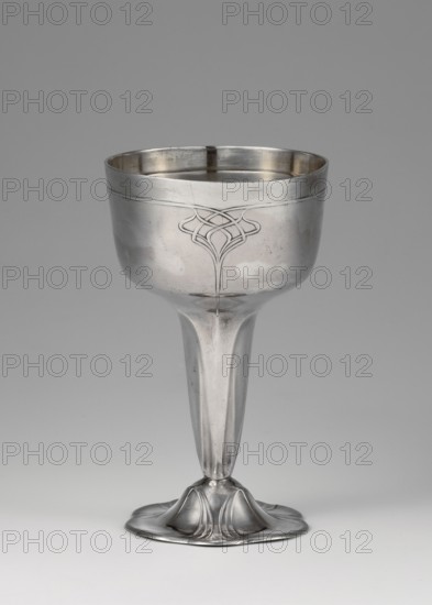 Art Nouveau silver cup by Orivit AG Cologne; goldsmith's manufactory; 1894–1905; 1906–1914 manufacturer; after takeover by WMF. Art Nouveau style; scrap. Silver Art Nouveau cup supported on a flower-shaped foot. Tall stem widening toward the top, hemispherical bowl with a slightly flattened bottom, decorated with a geometric-floral ornament. Dated 1906–1914, Cologne, Germany. Vessel. Height 12 cm; width 7.2 cm; weight 123 g., A metallic goblet photographed against a plain background, showing a bowl with a subtle engraved decorative motif on its front, a smooth tapering stem, and a rounded flared base with petal-like sculpted forms; visible colors include silver tones on the goblet and shades of gray in the background and surface reflections.