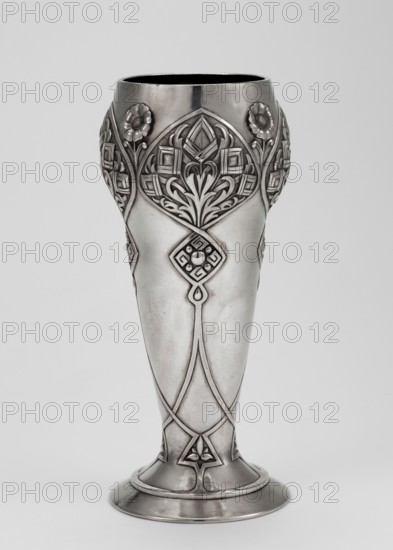 Art Nouveau vase, Khlebnikov goldsmith's workshop; 1840–1918, goldsmith. Scrap - purchase, purchase provenance. Art Nouveau style, geometric-floral ornament. Vase supported on a circular foot transitioning into a conical body, decorated with interlacing ribbons forming rhomboid reserves with geometric-floral decoration. Dated 1896–1908, Moscow, Russia. Vessel. Height 18.5 cm; width 8.1 cm; depth 7.8 cm; weight 322 g., A tall ornamental metal vase with a polished silver-gray surface standing against a light gray background, featuring ornate raised floral and geometric relief designs around its upper portion and along its shaft, with stylized flower motifs and curved leaf-like patterns, a flared rounded base with banded rims, smooth midsection contrasting with the detailed embellishments, and overall tones of silver, gray, and subtle darker gray shading.
