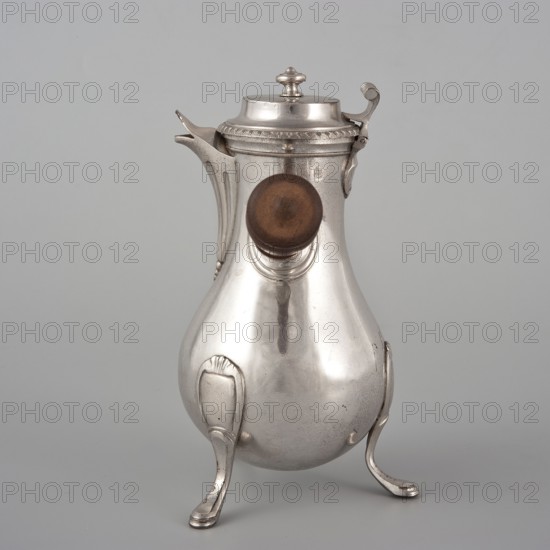 Coffee pot by F. Picard fl. ca. 1798–ca. 1809. Classification: vessel; function: coffee pot. Materials/objects: coffee pot, tableware item, jug. Date: 1798–1809. Place of origin: Paris, France. Dimensions: height 46.0 cm; width 8.5 cm; depth 8.5 cm; weight 248.2 g., A polished metal pitcher with a rounded pear-shaped body stands on a group of curved legs; the metal is primarily silver with a slightly aged patina and subtle darker spots. A short spout extends from one side near the top, and a hinged lid with a decorative finial sits atop the pitcher. A wooden knob in a warm brown tone is mounted on the front. The surface shows smooth reflective highlights and soft shadows, and the background is a uniform light gray.