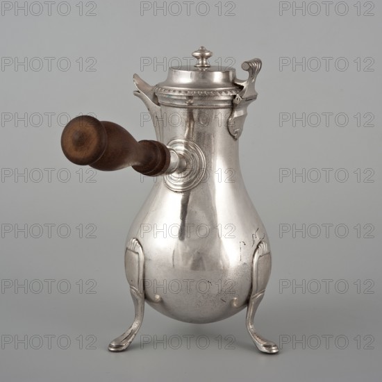 Coffee pot by F. Picard fl. ca. 1798–ca. 1809. Silver vessel, height 46.0 cm, width 8.5 cm, depth 8.5 cm, weight 248.2 g. Made in Paris, France, ca. 1798–1809; classification: coffee pot, tableware item, jug., A metallic silver pot with a bulbous body stands on a group of three curved legs, each leg having a decorative ridge and a slightly flattened foot, and the pot has a hinged lid with a small rounded finial and ornate hinge pieces; a wooden handle in a warm brown extends horizontally from one side, attached to a circular metal mount, and the surface of the pot shows subtle scratches, reflections, and areas of patina against a pale grey background.