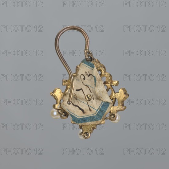 Earring, Renaissance style, 19th century, Poland, jewelry, height 3.5 cm, weight 7 g, A small decorative earring hangs against a plain gray background, featuring a curved metallic hook in a tarnished gold tone attached to an ornate gold-colored metal frame with curving, baroque-inspired shapes. Inside the frame is a torn piece of off-white paper with blue edges and dark ink marks, secured by a tiny metal pin. Three small round pearls dangle from the lower part of the frame, and visible colors include gray, gold, off-white, blue, and creamy pearl tones.