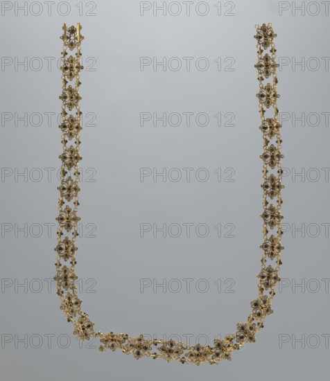 Necklace, rosette iconographic, jewelry, women's accessories, mid-19th century, Italy, weight 16.57 g, length 37.5 cm, A delicate gold necklace composed of a linked series of floral-shaped motifs forming a long U-shape against a pale gray background, each motif featuring small dark accents at the centers and tiny connecting loops, the gold showing warm yellow tones and the accents appearing deep brown to black, the overall composition presenting an ornate, lacy appearance with a few curved sections at the bottom and symmetrical vertical strands rising to matching clasps at the top.