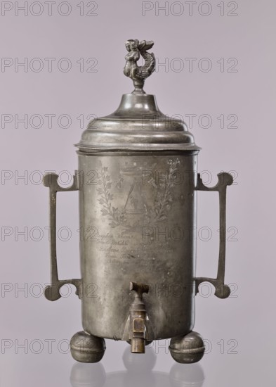 Watering can of the carpenters' guild, probably Warsaw, cylindrical, supported by three balls, a brass tap with a valve mounted in the lower part; on the sides two rectangular, broken, slightly profiled handles; closed watering can with a profiled, arched lid, topped with a plastic mermaid figurine; on the mantle, above the tap, engraved emblem of the carpenters' guild under a crown, enclosed in a plant wreath, below the inscription: Boguslaw Neuman Beysicz Meyster / Tomasz Prokulski Beysicz Meyster / Bartlomie Baxalarowicz the elder Towrz: / Franz Friser Podstarszy / Antony Jaszesky Podskarby / Anno 1821, 1821, Poland, vessel, guild memorabilia, height 50.5 cm, width 31.5 cm, depth 29 cm, A metallic tankard-like vessel with a domed lid topped by a small sculpted figure, the vessel is cylindrical with a pair of symmetrical handles extending vertically from near the top to near the bottom, a spigot near the base, and rests on three rounded feet. The metal shows an aged, slightly tarnish...