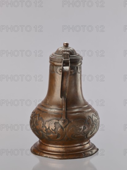 Jug. On a circular, stepped base, the body bulges in the lower part, decorated with a repoussé leafy twig and, at the rim, an eagle with spread wings. Above the two stepped areas is a neck with a spout. Repoussé leaves under the rim and along the rim. The hemispherical handle, fastened with rivets; the lid is hinged with a finger grip, arched, decorated with a leafy rosette and topped with a ball. Maker: Szewczykowski, Roman 1849–1901 — role unknown. 1st half of the 18th century, Poland. Vessel. Height 39.5 cm; width 23.9 cm; depth 28.4 cm., A single metal jug with a hinged lid sits against a plain light gray background, showing a rounded base that narrows into a neck and flares again at the top; the surface of the jug is a warm brownish-bronze with areas of darker patina and subtle greenish tarnish, and it features ornate raised floral and foliate decoration around its bulbous midsection as well as decorative bands near the top and base; a vertical handle with a heart-shaped fastening...