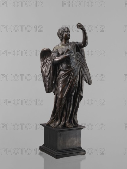 Statue - Angel, Renaissance. Figure of a standing angel with his left hand raised, the other raised to chest height, originally holding a cross or an element of the Arma Christi. Square wooden base with profiles on the upper and lower edges, secondary. 16th century. Sculpture. Height 44 cm, width 12 cm, depth 12.5 cm., A dark bronze statue of a winged figure stands on a dark wooden pedestal against a neutral gray background; the figure wears flowing drapery with detailed folds and holds one arm raised while the other rests near the chest, the wings show carved feather details, the bronze has subtle highlights of lighter brown and greenish patina, and the pedestal appears black to dark brown.